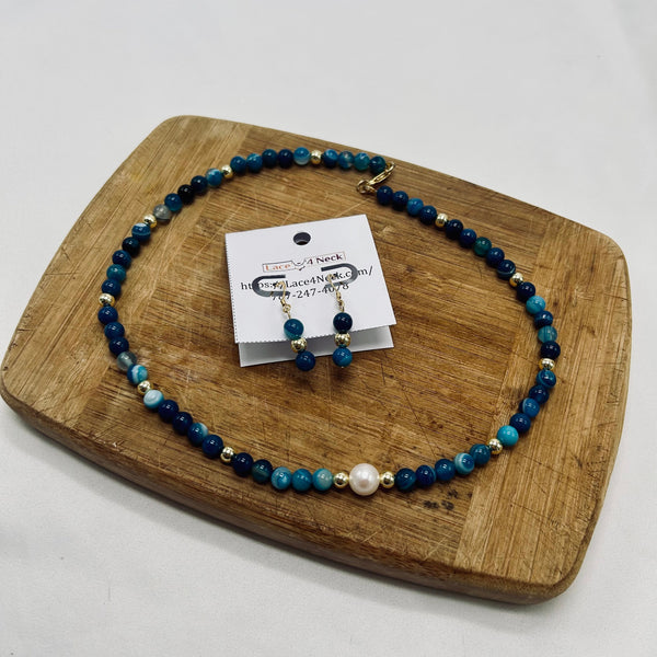 Beaded necklace and earrings on a wooden board with a product card