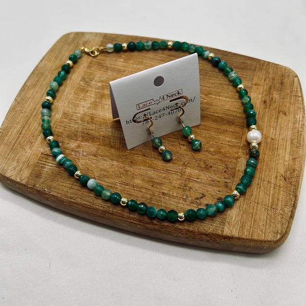 Green beaded necklace and earrings on a wooden board with a card displaying the brand 'Lace & Neck'.