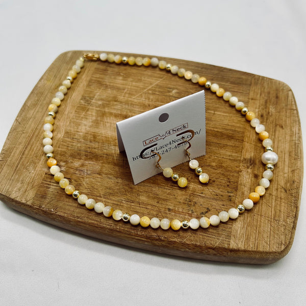 Pearl necklace and earrings set on a wooden board with a card