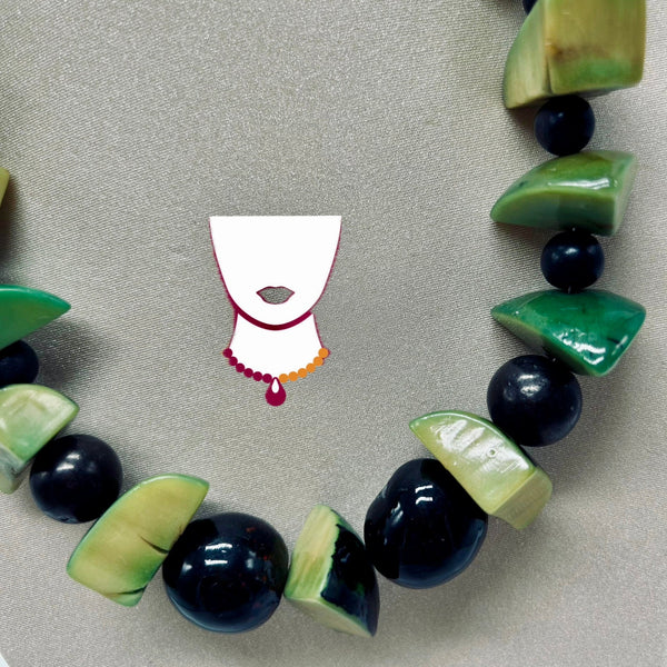 Necklace with green and black beads on a gray background
