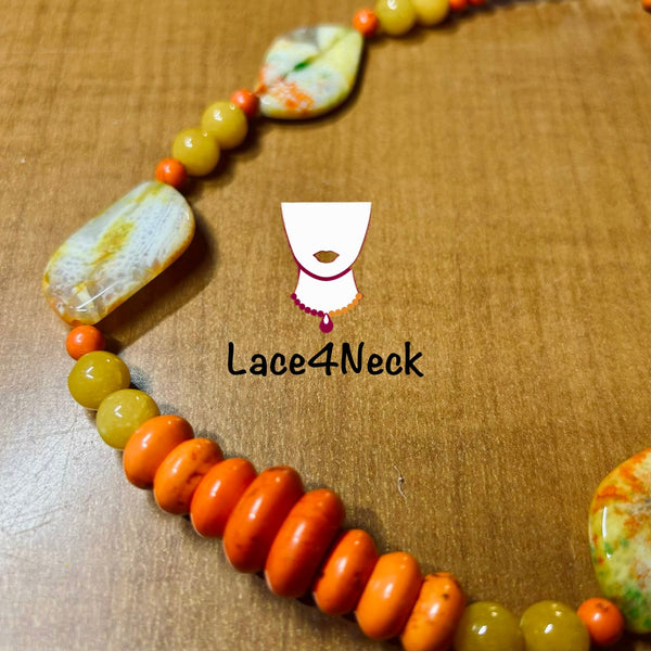 A beaded necklace with large orange disc beads, yellow-green round beads, and marbled white and orange stone chips, displayed on a brown wooden surface. A white logo for 'Lace4Neck' is overlaid in the center.