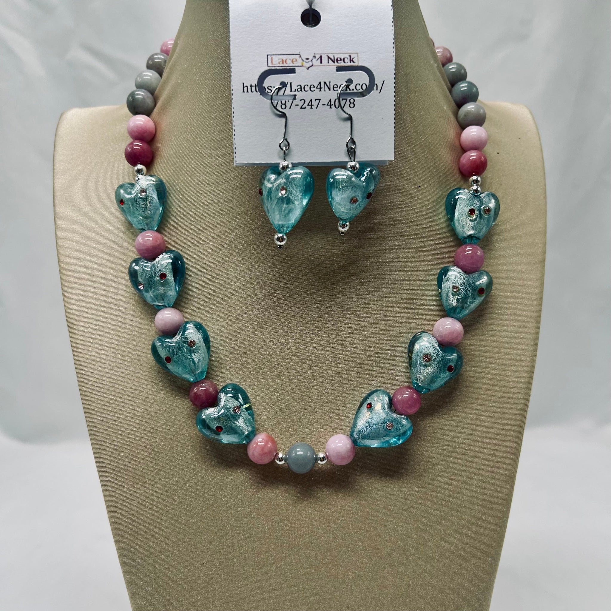 Necklace and earrings set on a tan display with a visible brand tag.