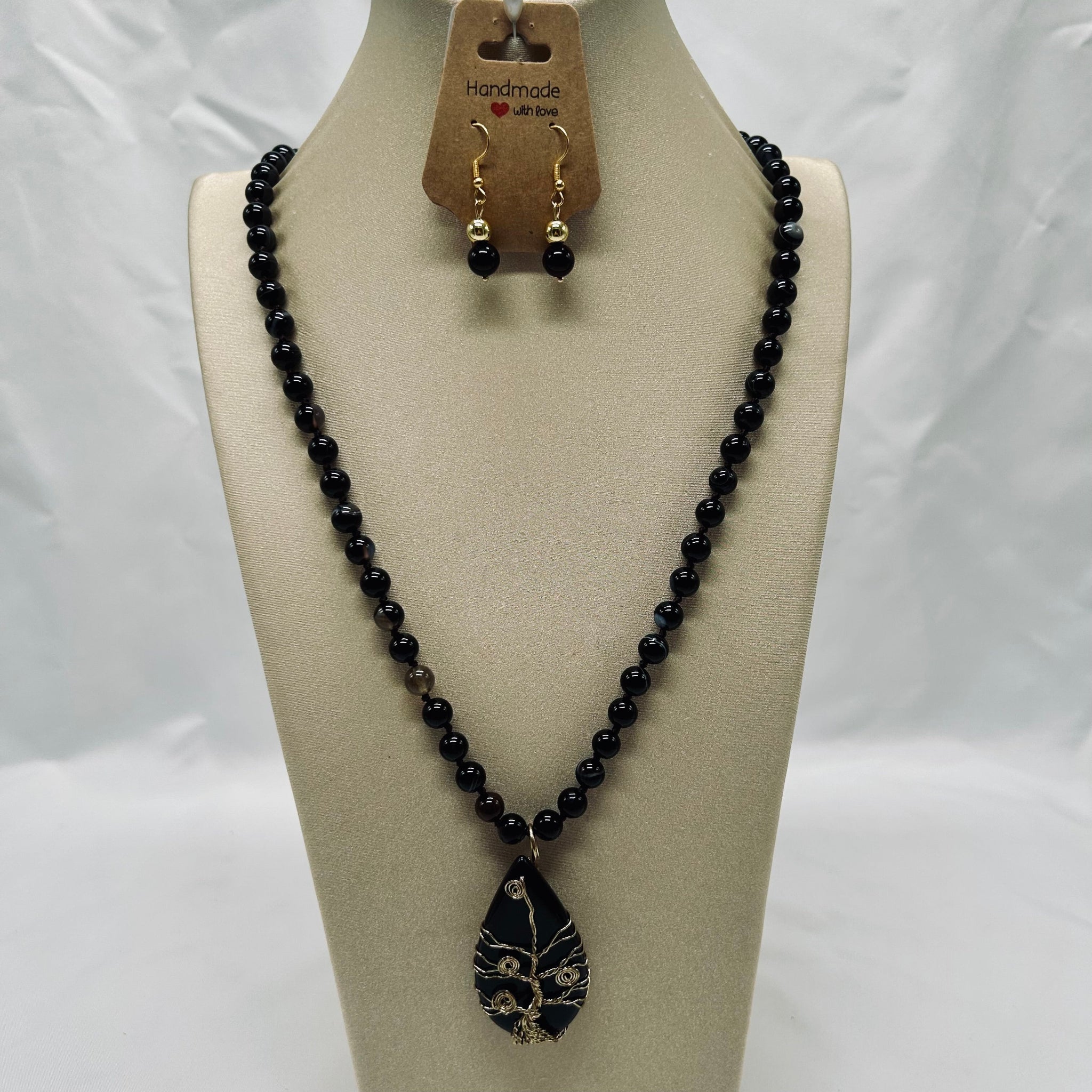 Black beaded necklace with a pendant on a mannequin bust against a white background
