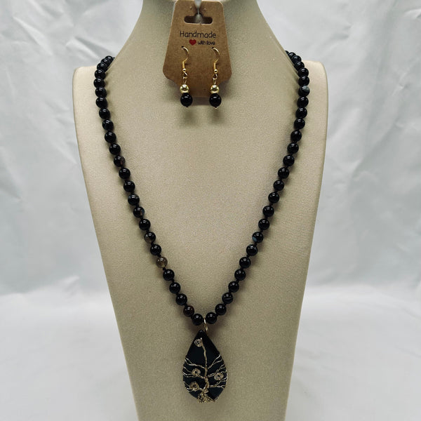 Black beaded necklace with a pendant on a mannequin bust against a white background