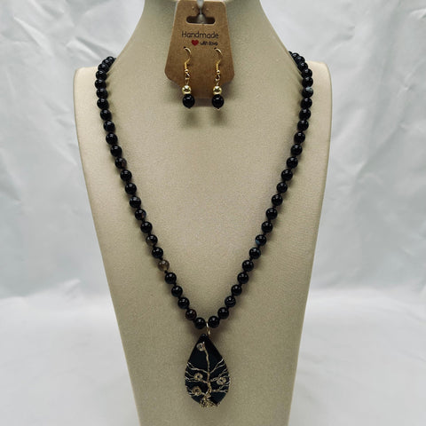 Black beaded necklace with a pendant on a mannequin bust against a white background