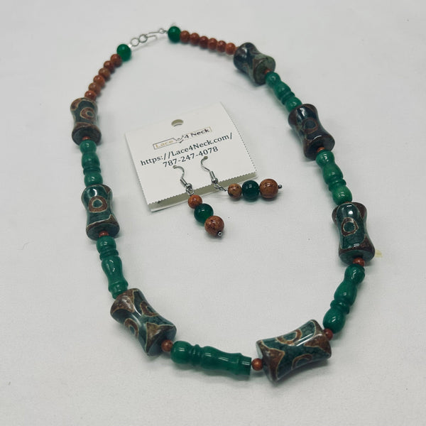 A beaded necklace and matching drop earrings displayed on a white background. The jewelry features dark green cylindrical beads, brown and reddish-brown round beads, and dark brown/black cylindrical beads with white and green patterns.