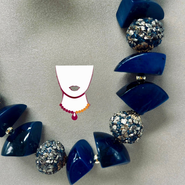 Blue beaded necklace with glittery accents on a gray background