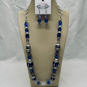 Necklace and earrings set with blue and silver beads on a beige display stand.