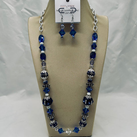 Necklace and earrings set with blue and silver beads on a beige display stand.