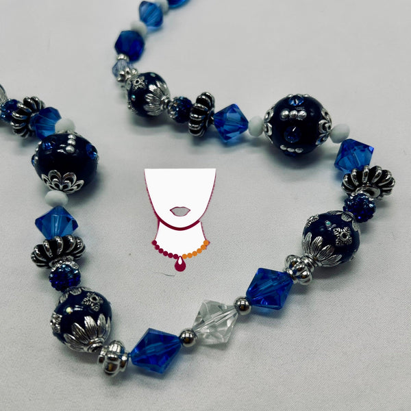 Necklace with blue, silver, and clear beads on a light gray background