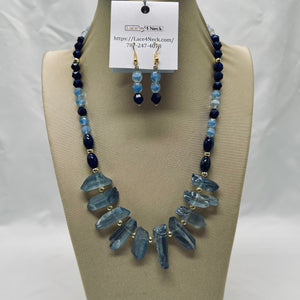 Necklace and earrings set with blue beads on a beige stand