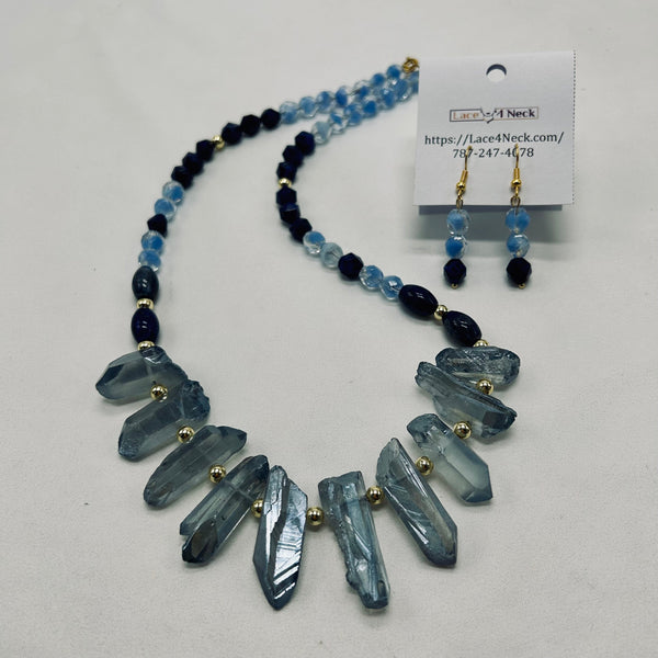 Necklace with blue and black beads and crystal-like pendants on a white background, with a matching earring set.