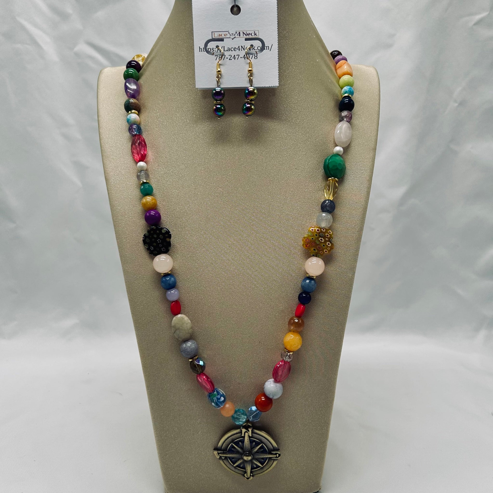 Colorful beaded necklace and earrings on a tan display stand with a white background
