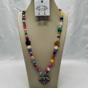 Colorful beaded necklace and earrings on a tan display stand with a white background