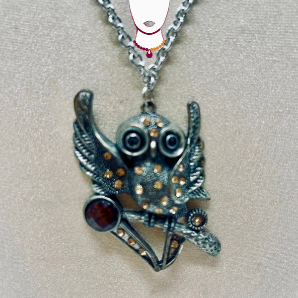 Silver owl pendant with gemstones on a chain against a light gray background
