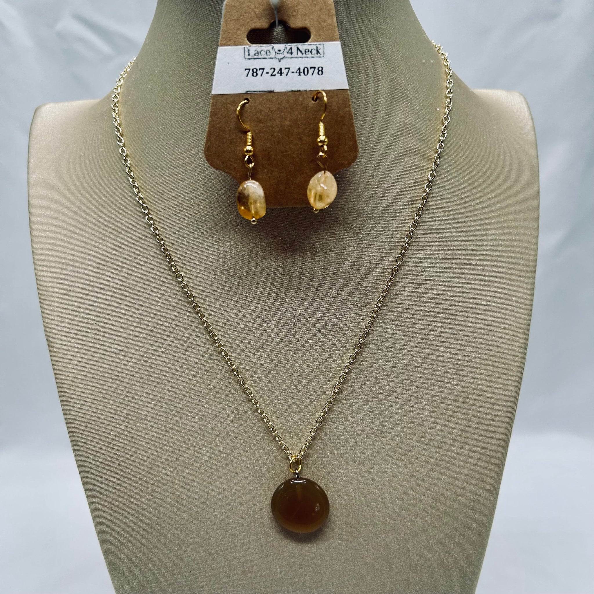 Necklace and earrings on a mannequin bust with a visible brand tag.