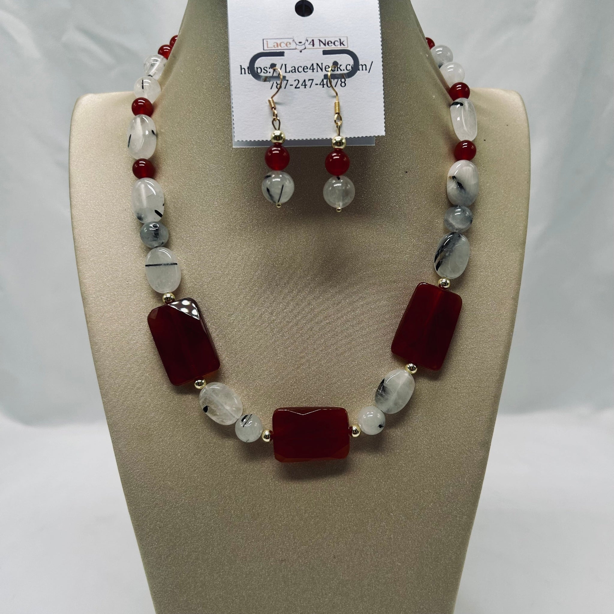 Necklace and earrings set on a mannequin bust with a visible brand tag.