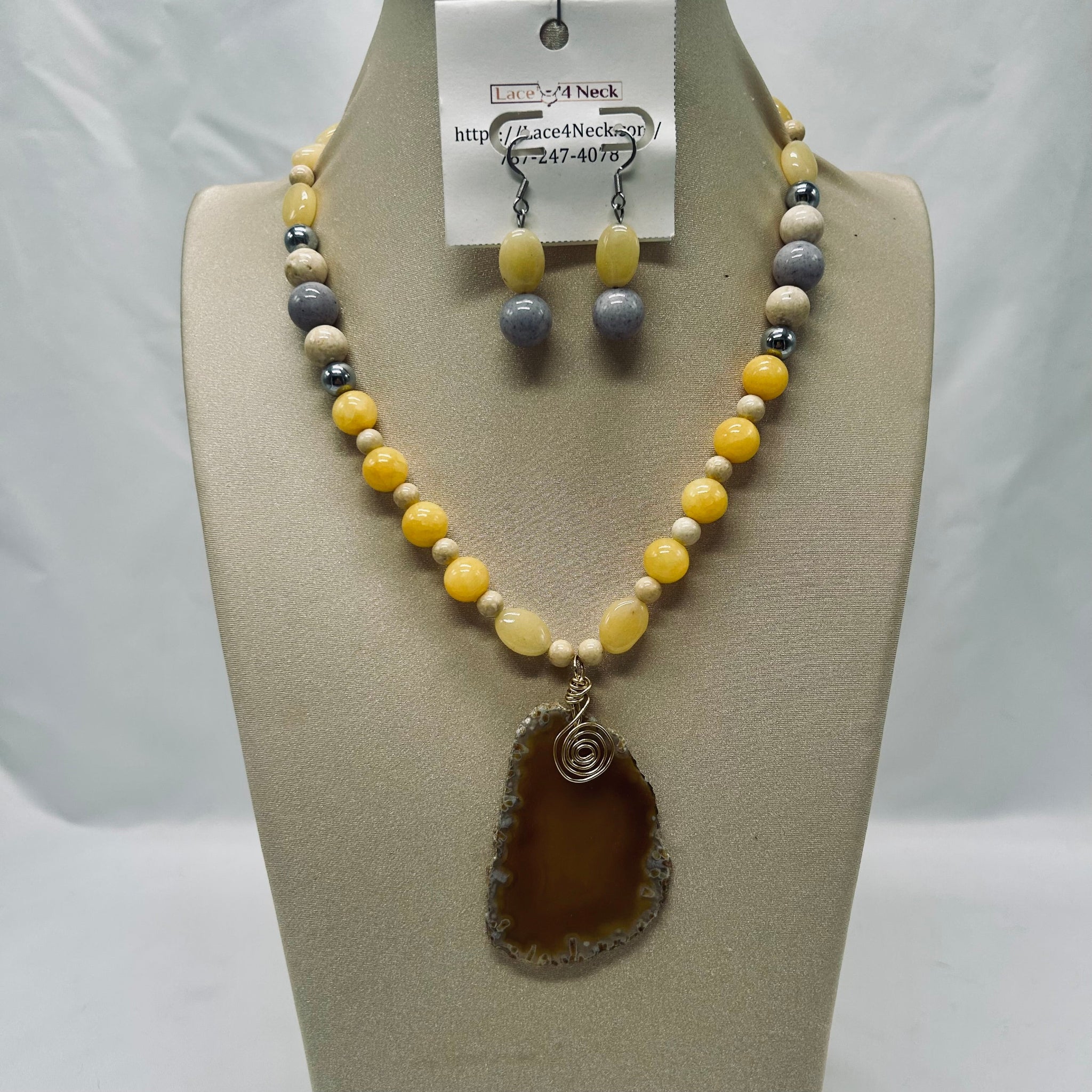 Beaded necklace and earrings set on a mannequin bust with a visible brand tag.