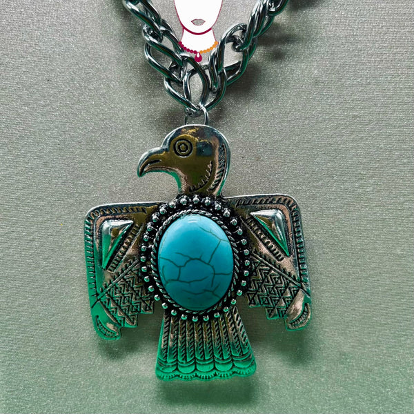 Silver and turquoise eagle pendant on a chain against a gray background