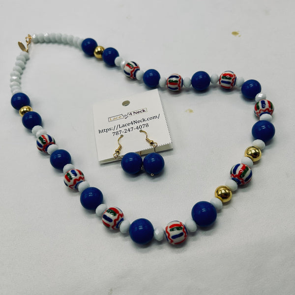 A beaded necklace and matching drop earrings displayed on a white surface. The necklace features large royal blue beads, small white beads, and decorative striped glass beads in red, white, and blue, separated by small gold spacer beads.