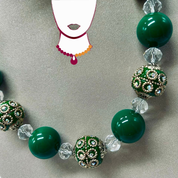 Necklace with green beads and silver accents on a gray background