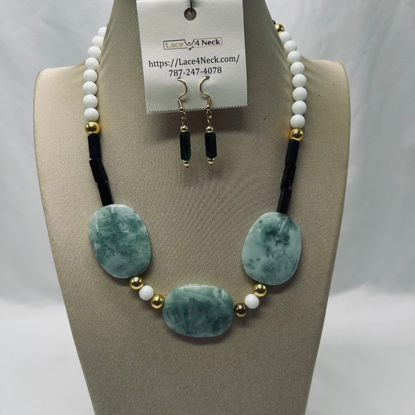 Jewelry set with necklace and earrings on a mannequin bust, featuring green stones and white beads.
