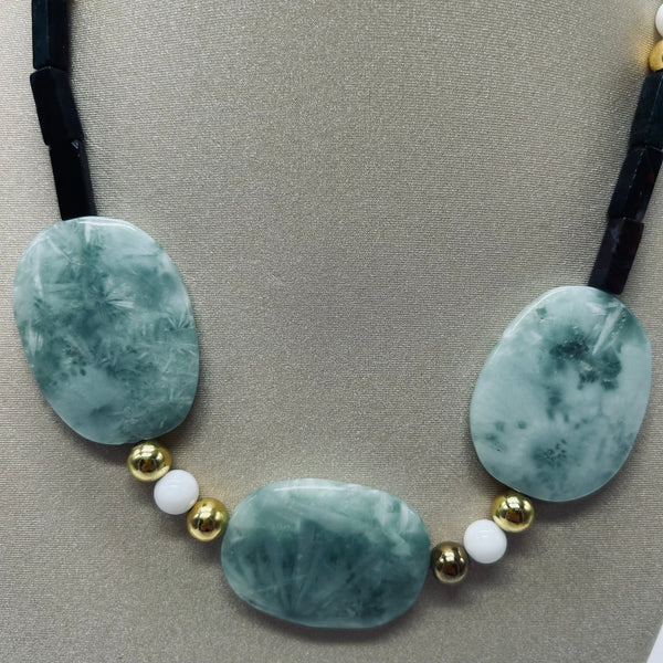 Necklace with green oval beads and gold and white spherical beads on a gray background