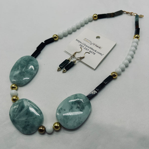 Necklace with green stones and white beads on a light gray background
