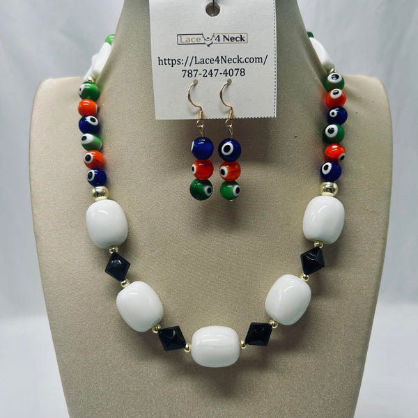 A beaded necklace and matching drop earrings displayed on a beige jewelry bust. The necklace features large white oval beads, black faceted beads, and evil eye beads in blue, red, and green, separated by small gold spacer beads.