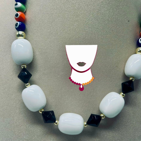 A beaded necklace with large white oval beads, dark navy faceted beads, and colorful evil eye beads, displayed on a neutral gray background with a decorative necklace stand graphic.