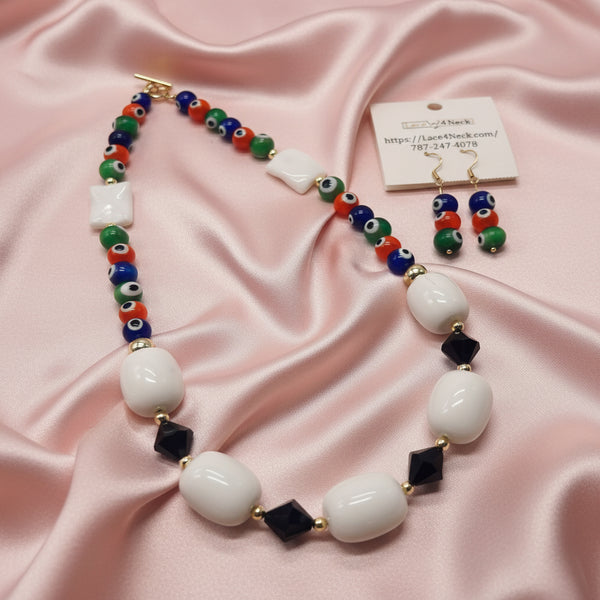 A beaded necklace and matching drop earrings displayed on a white background. The necklace features large white oval beads, dark navy square beads, and small evil eye beads in green, blue, red, and white.