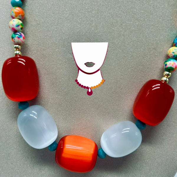 Colorful beaded necklace with red, white, and orange beads on a neutral background.