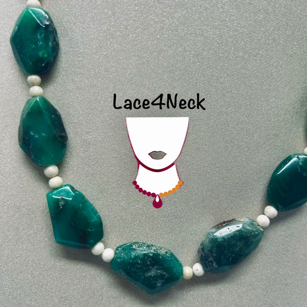 A beaded necklace with large polished emerald-green stones separated by small white beads, displayed on a gray fabric background. A stylized white neck graphic with the text 'Lace4Neck' is overlaid in the center.