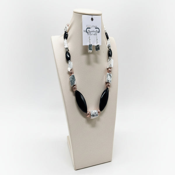 Necklace with black and silver beads on a display stand with a green background