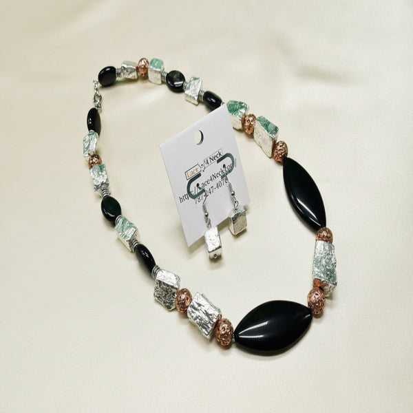 Necklace with black, green, and clear beads on a green background