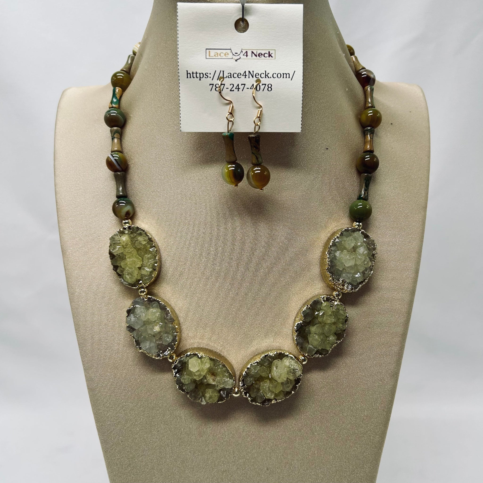 Necklace and earrings set on a mannequin bust with a visible brand tag.