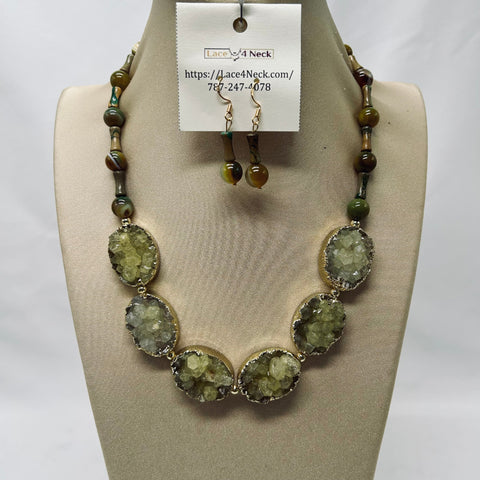 Necklace and earrings set on a mannequin bust with a visible brand tag.