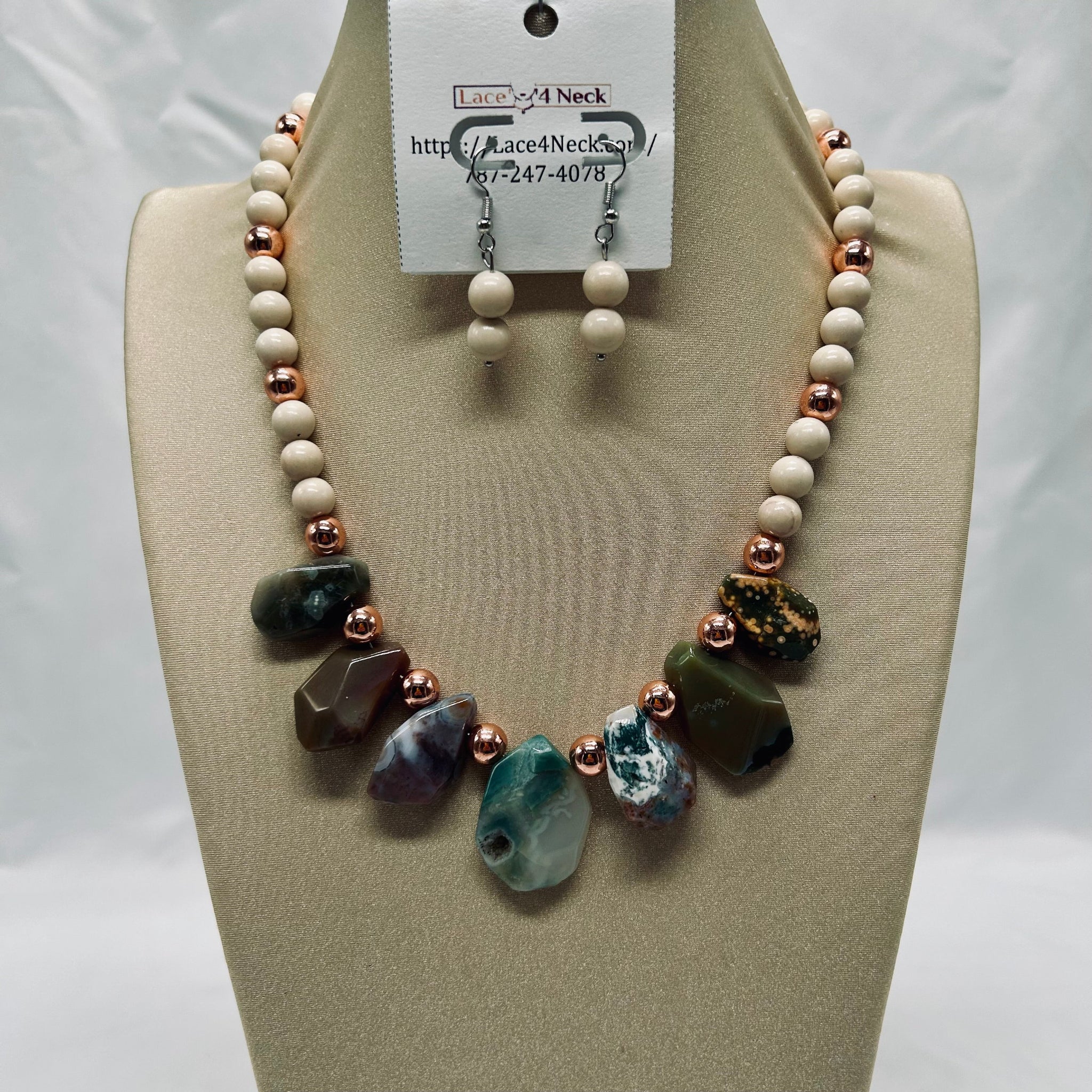 Necklace and earrings set on a mannequin bust with a visible brand tag.