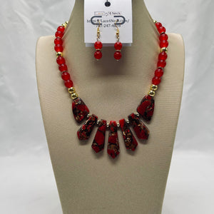 Red beaded necklace and earrings on a mannequin bust with a visible brand tag.