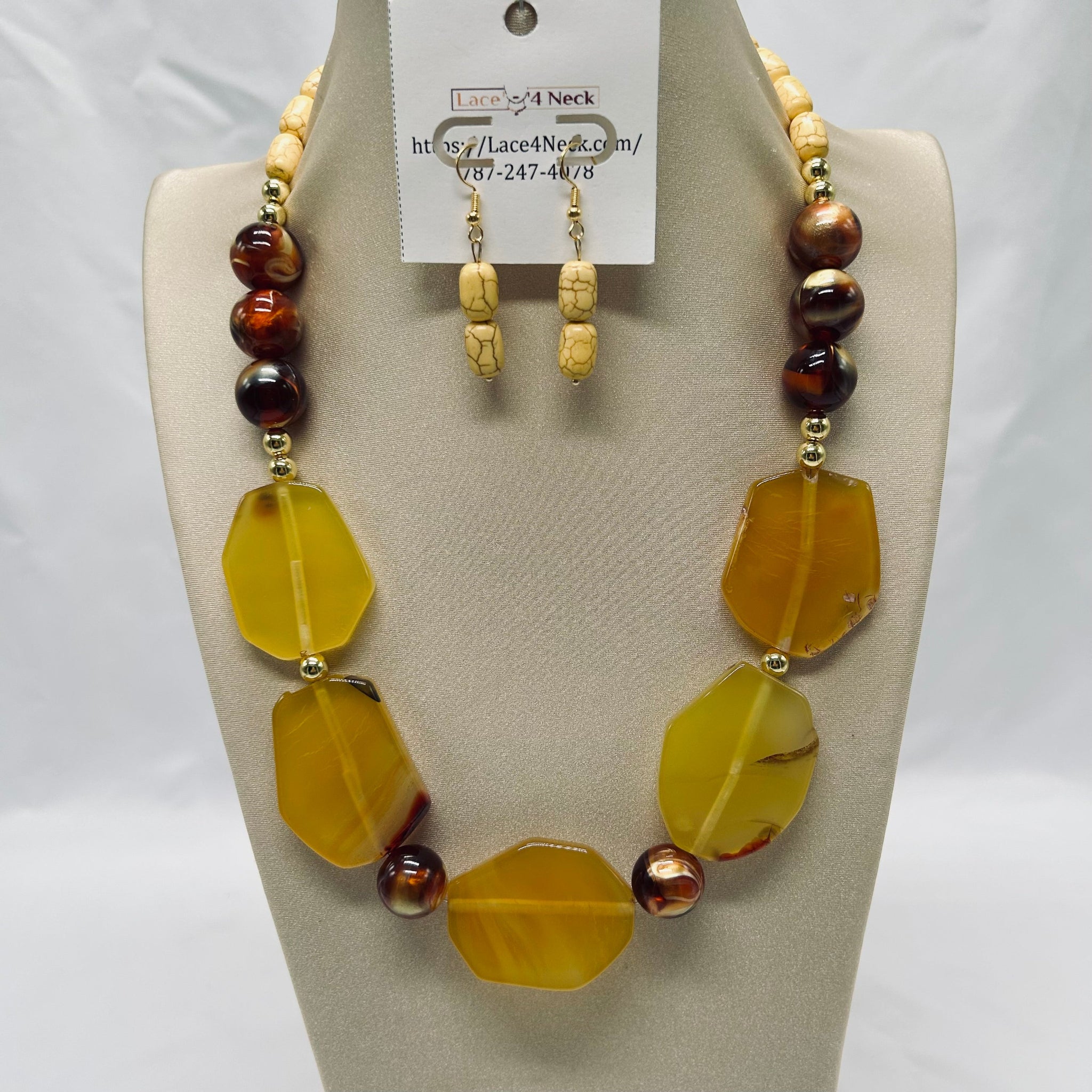 Necklace and earrings set on a mannequin with a visible brand tag.