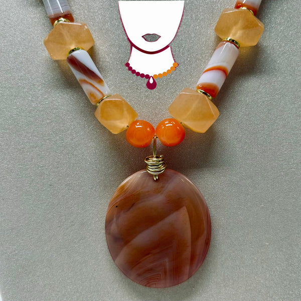 Necklace with large brown pendant and orange beads on a neutral background