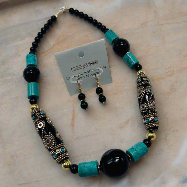 Necklace and earrings set with turquoise and black beads on a gray background