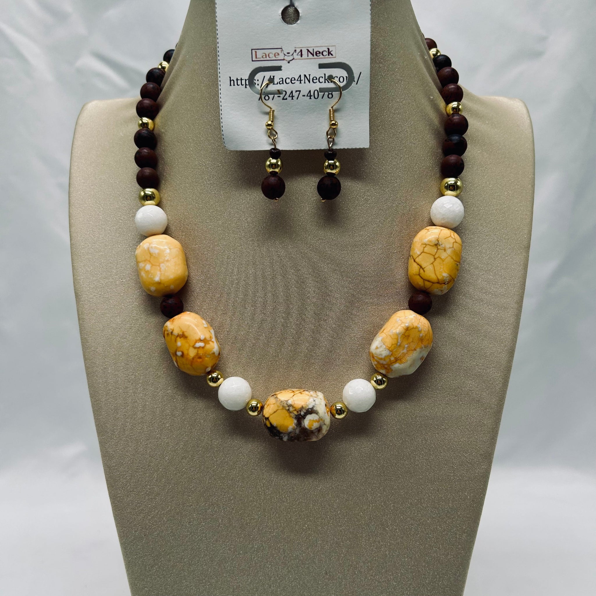 Necklace and earrings set on a mannequin bust with a visible brand tag.