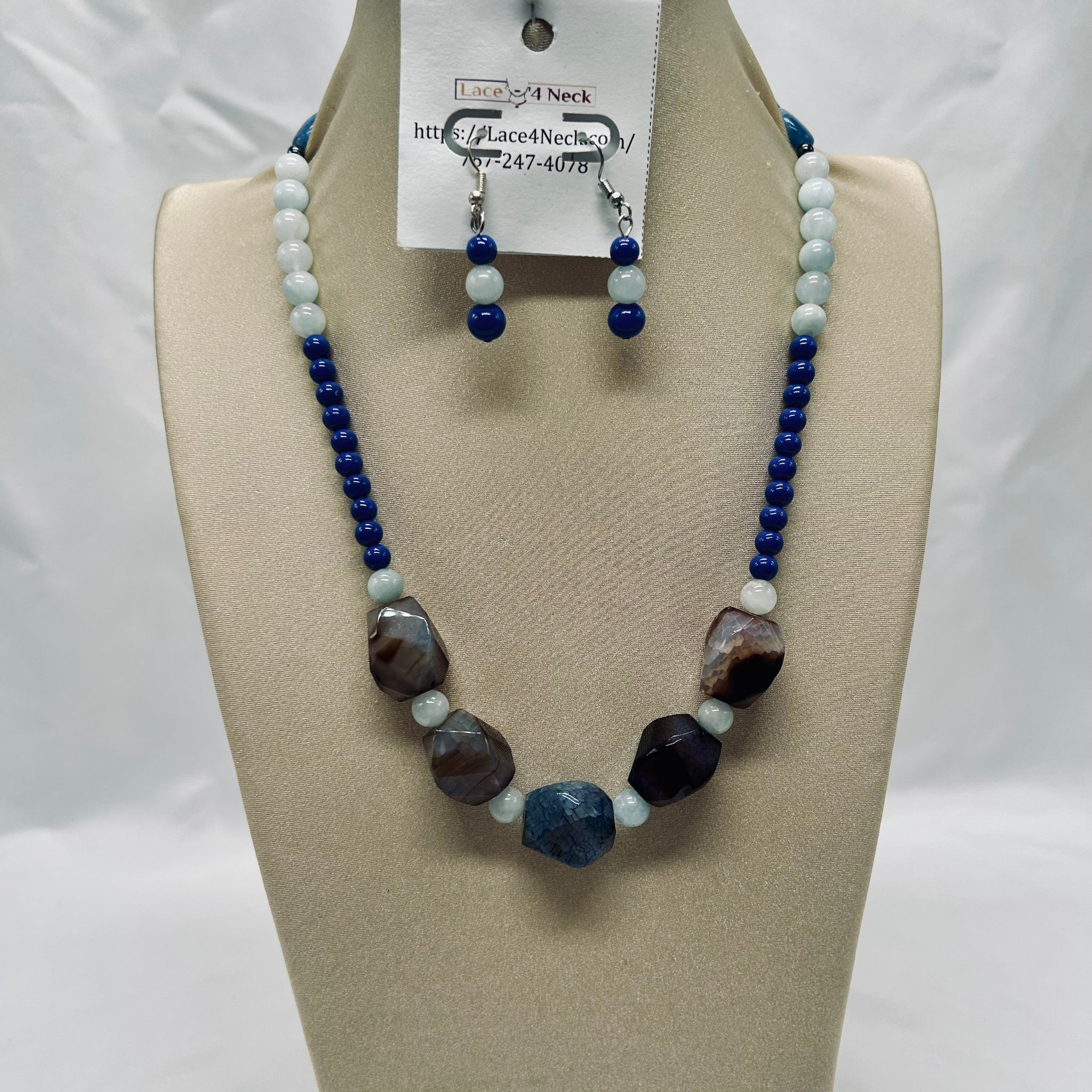 Beaded necklace and earrings set on a mannequin bust with a visible brand tag.