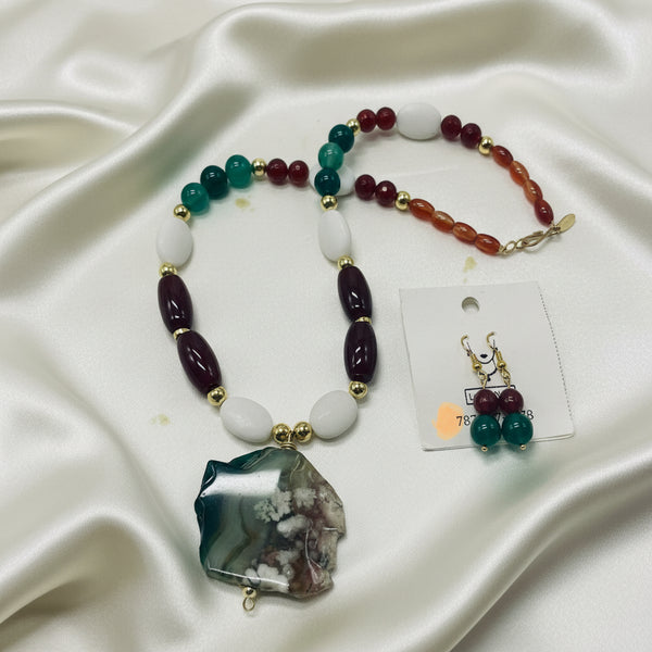 A beaded necklace with a large agate geode pendant, displayed alongside matching drop earrings on a white card against a light background.