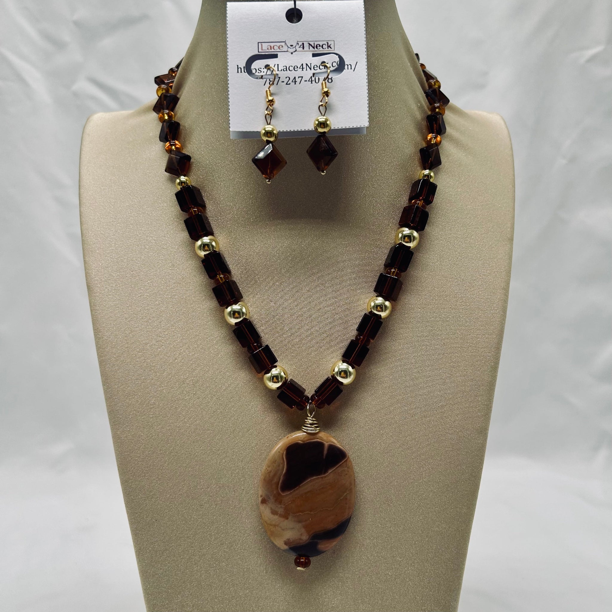 Necklace and earring set on a mannequin bust with a visible brand tag.