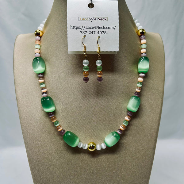 A beaded necklace and matching drop earrings displayed on a beige jewelry bust. The necklace features translucent green oval beads, small pastel beads in pink, white, and purple, and gold-toned spacers.