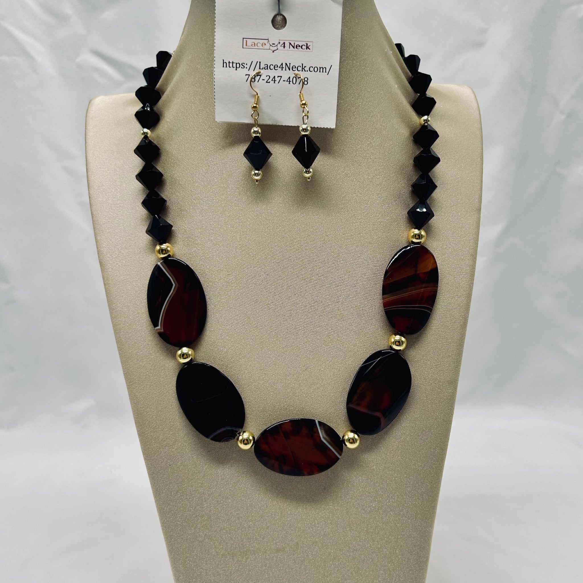Necklace and earrings set on a mannequin bust with a visible brand tag.