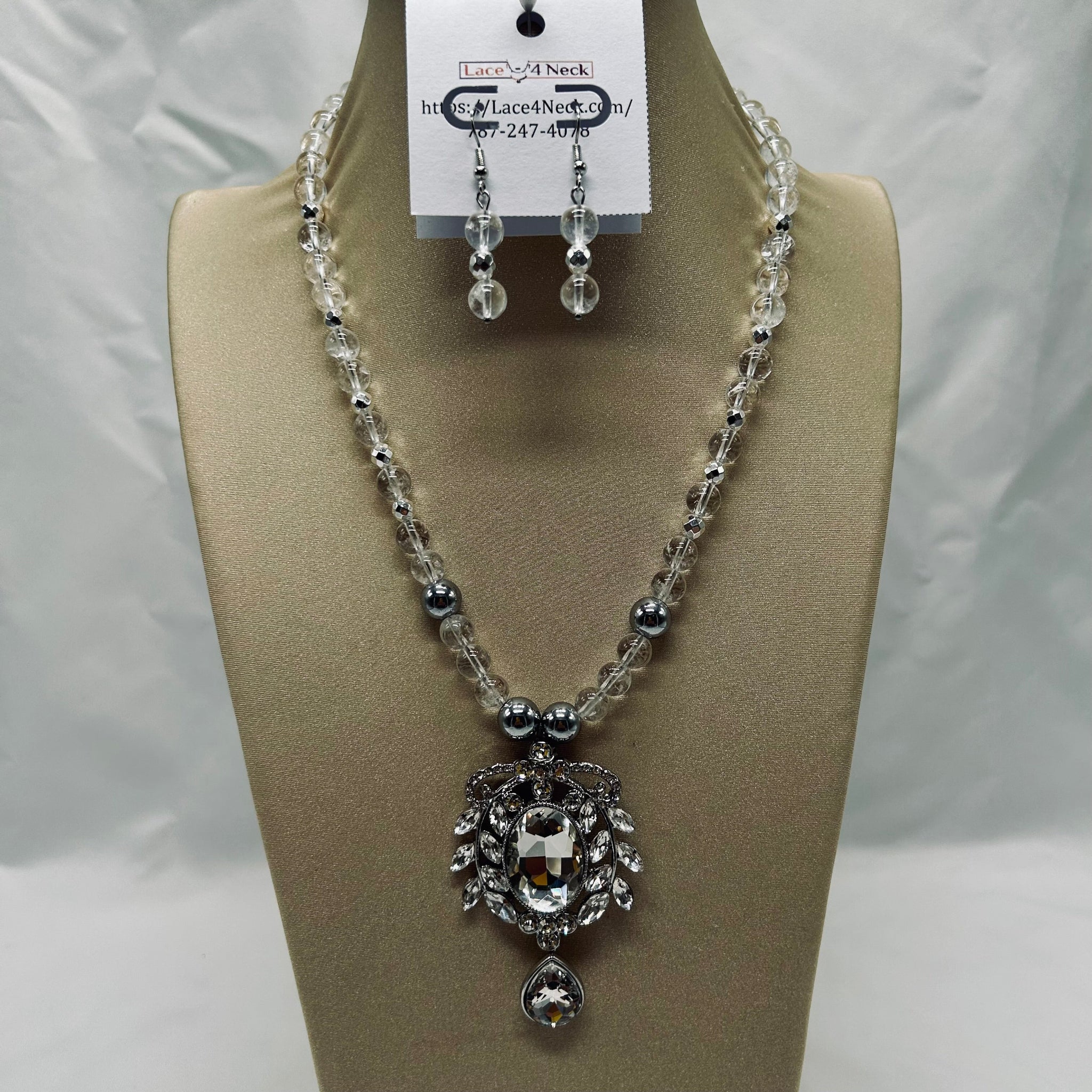 Necklace and earrings set on a mannequin bust with a visible brand tag.