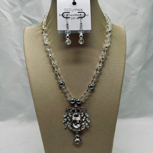 Necklace and earrings set on a mannequin bust with a visible brand tag.